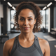 Close-up portrait of a happy, confident woman in athletic wear, smiling slightly in a gym setting.