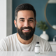 Close-up portrait of a diverse man in his late 20s to early 30s, with a well-groomed beard and smooth skin, smiling confident